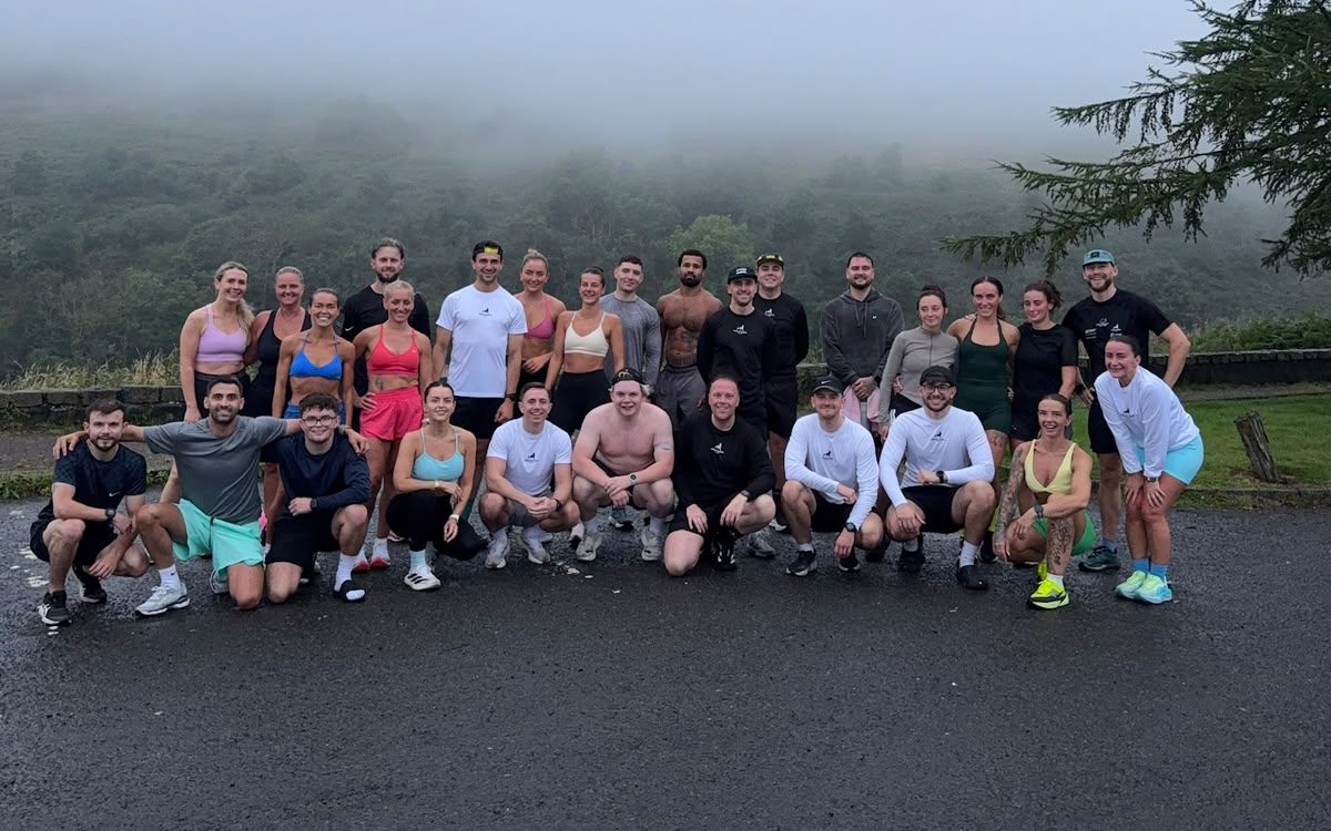 A large group of Wolftuna members posing together after a run on a misty hilltop