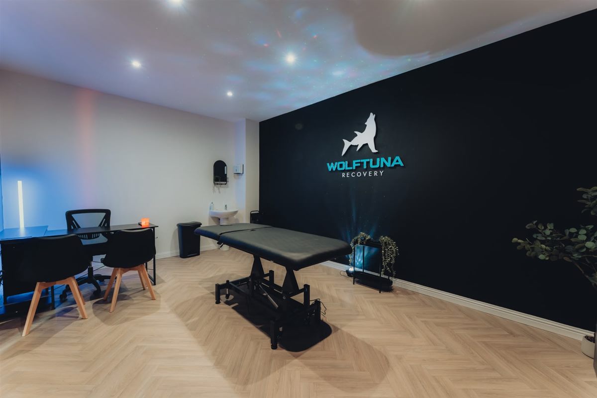 The Wolftuna Recovery treatment room with a massage table and the Wolftuna Recovery logo on the wall